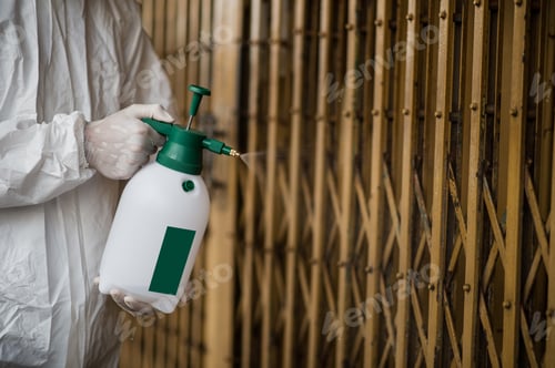 Preview: Man in protective suit and mask sprays disinfectant