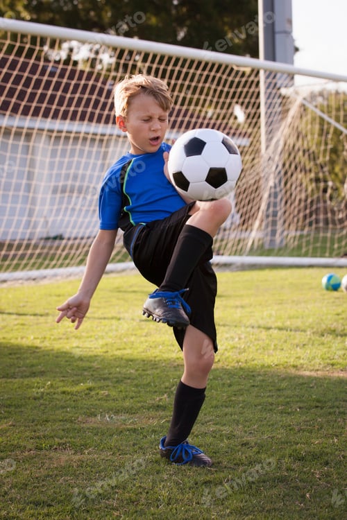 Preview: Boy playing keepy uppy with football on pitch