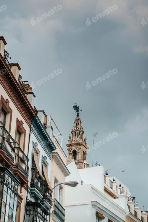 Preview: upper part of tower of giralda in Seville peeking between roofs of adjoining houses