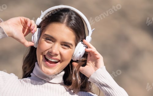 Preview: Front portrait of happy woman with headphones listening to audio with defocused background