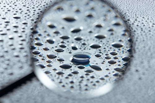 Preview: selective focus of magnifying glass and contact lense on grey background with water drops