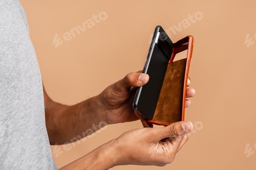 Preview: African American man holding leather brown phone case. Stylish accessory concept