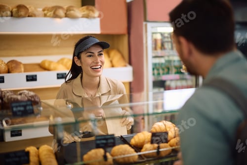 Preview: Happy bakery worker talking to her customer.