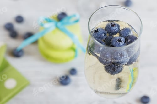 Preview: Glasses of champagne with blueberries and macaroons