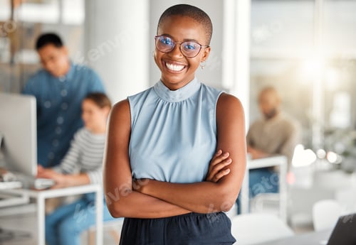 Preview: Young happy african american businesswoman standing with her arms crossed while in an office. Confi