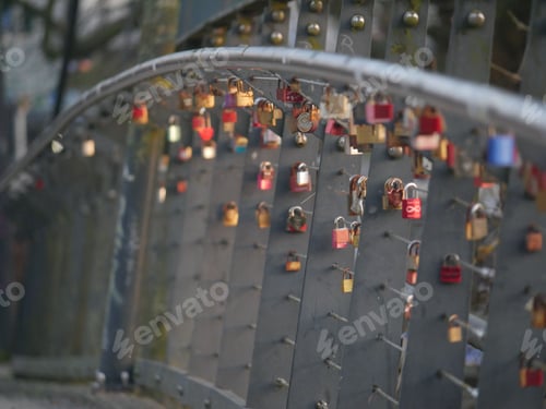 Preview: Close-up of colorful locks suspended from a steel bridge, hanging in the sunlight