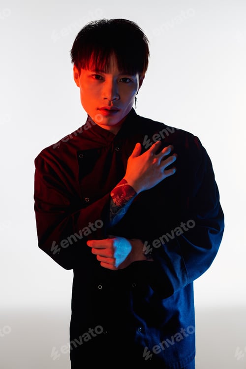 Preview: Stylish asian man poses confidently with artistic lighting and modern attire in an urban setting