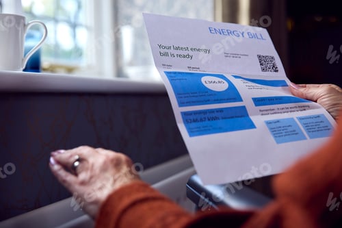 Preview: Close Up Of Senior Woman In Wheelchair With Energy Bill By Radiator In Cost Of Living Energy Crisis