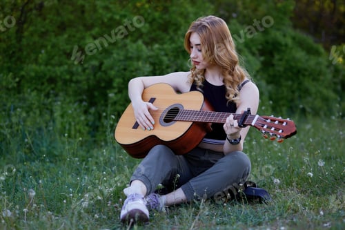 Preview: Beautiful caucasian woman with an acoustic guitar playing music outside