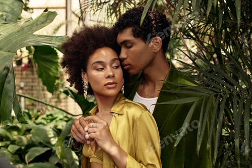 Preview: Young couple embraces in lush greenhouse filled with vibrant greenery and love