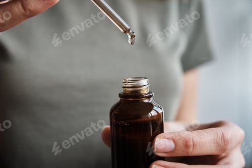 Preview: Woman holds bottle with cosmetic serum and essential oil
