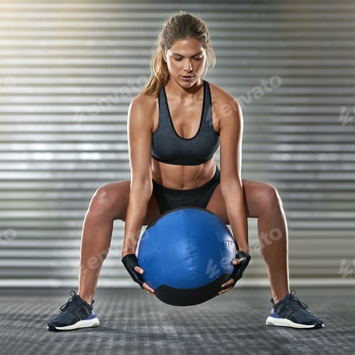 Preview: Lets pick it up. Full length shot of a young woman working out with a medicine ball at the gym.