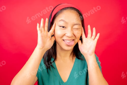 Preview: Playful Young Woman Making Faces on Red Background