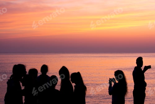 Preview: Silhouettes of group of people on the beach waiting the sunrise against the sea