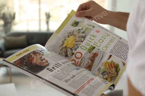 Preview: Man reading cooking magazine at home, closeup
