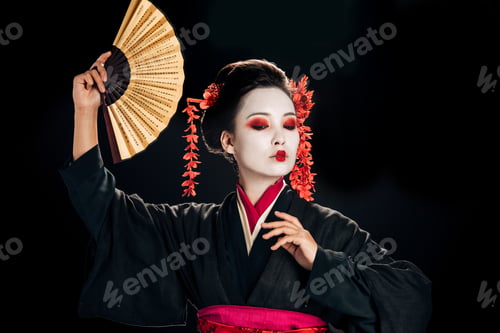Preview: geisha in black kimono with red flowers in hair dancing with traditional asian hand fan isolated on