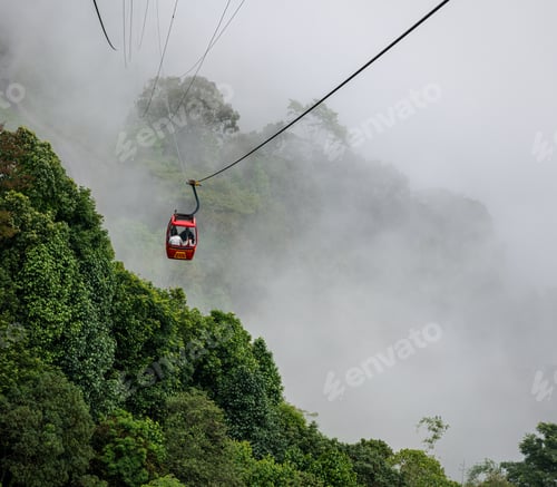 Preview: Ropeway above the hills covered in greenery and fog at daytime - tourism concept