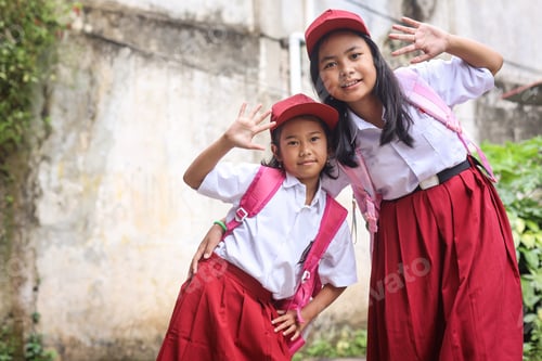 Preview: Happy Indonesian schoolgirls of elementary school waving hand look at camera
