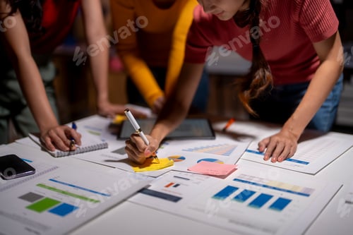 Preview: Business team working late analyzing financial charts using sticky notes