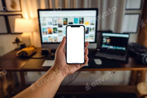 Preview: hand holding smartphone with blank screen in home desk