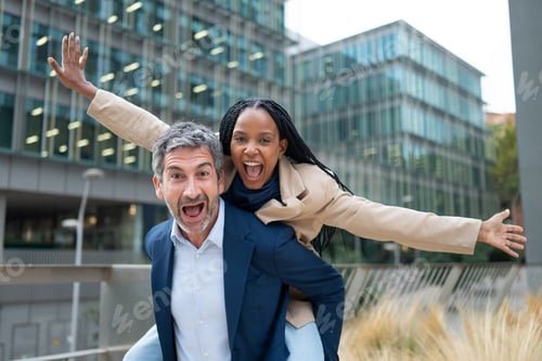 Preview: Business colleagues having fun riding piggyback on a city street