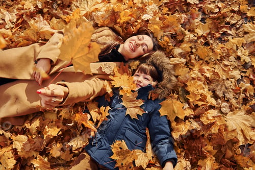 Preview: Laying down on the leaves. Mother with her son is having fun outdoors in the autumn forest