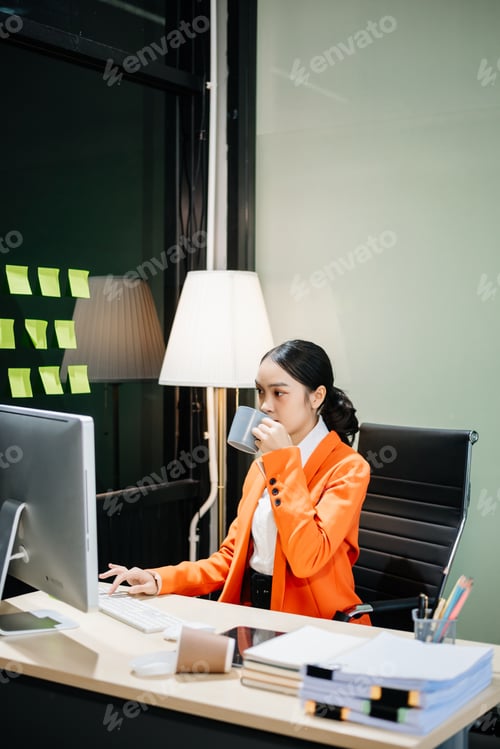 Visualização: Jovem mulher bonita digitando no tablet e laptop enquanto está sentada no trabalho