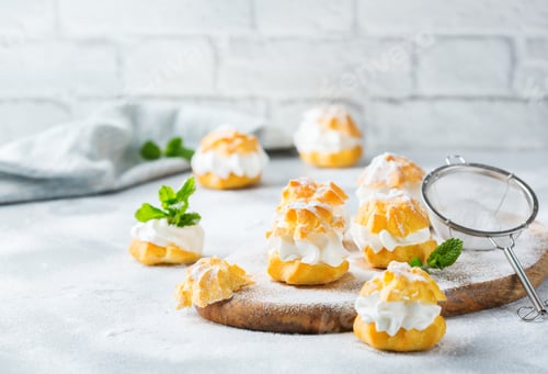 Preview: Delicious sweet profiteroles with cream on a modern kitchen table