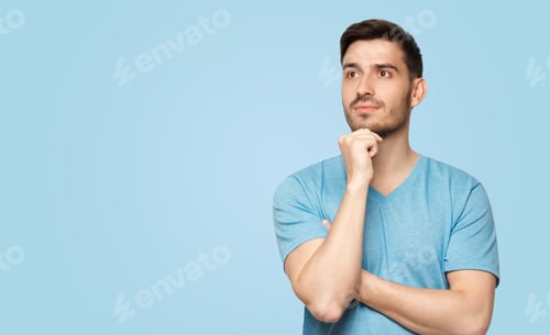 Preview: Banner of young man in blue t-shirt with dreamy cheerful expression, thinking