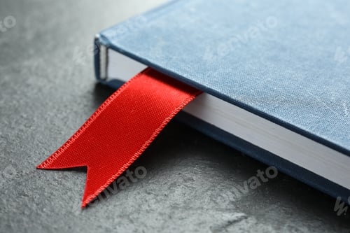 Preview: Planner with red ribbon bookmark on grey textured table, closeup