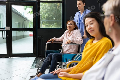 Preview: Wheelchair user consulting doctor during health check at modern hospital lobby
