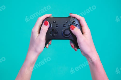 Preview: POV of female hands gaming with video game controller gamepad isolated on a blue background studio.