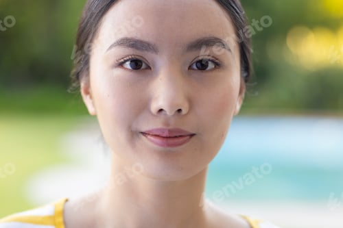 Preview: Smiling young asian woman with natural makeup posing outdoors, enjoying sunny day