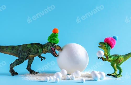Preview: Cute green dinosaur in knitted hats playing snowballs. Happy winter holidays card.
