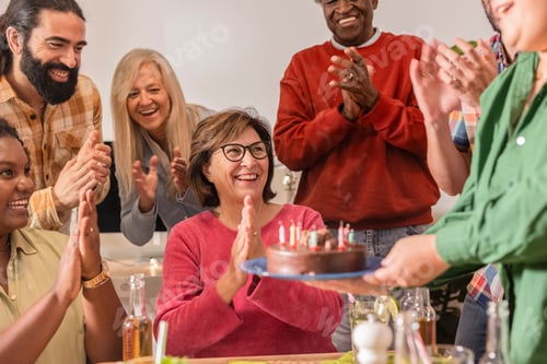 Preview: Diverse group clapping celebrating birthday with cake and candles