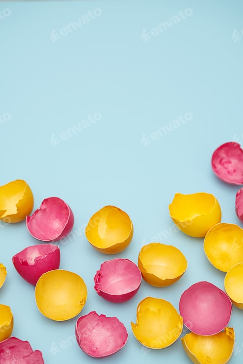 Preview: Cracked Yellow and Pink Easter Eggshells on Blue. Flat Lay with Copy Space.