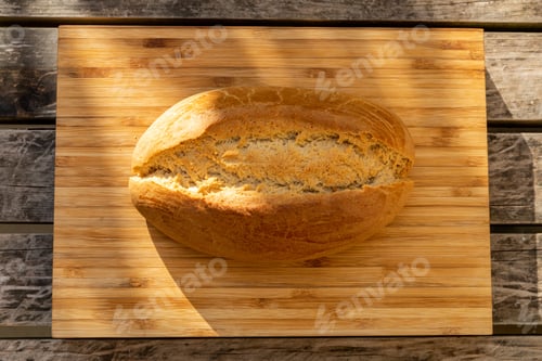 Preview: Horizontal shot of sourdough bread on a light wood cutting board on a darker wood surface