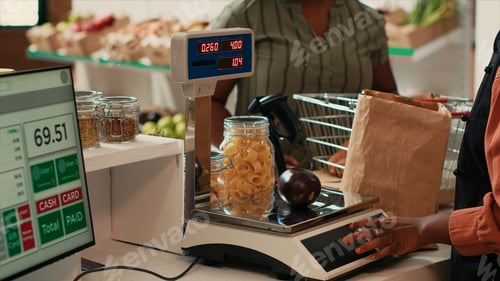 Preview: Merchant using scale at cash register checkout in organic shop