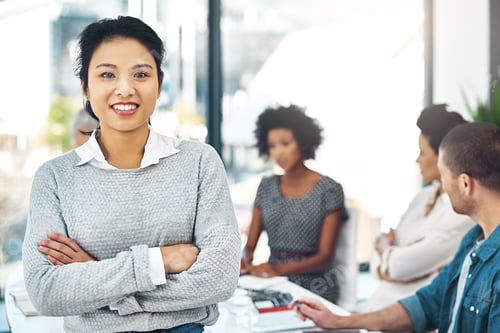 Preview: Portrait of a smiling businesswoman standing in a boardroom with colleagues in the background