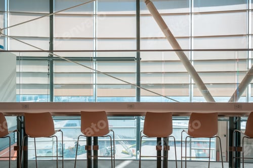 Preview: Row of chairs with wooden counter table on window glass in airport