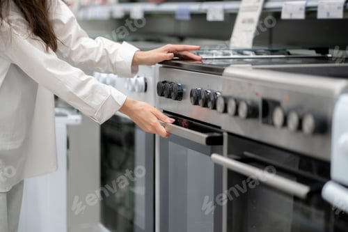 Preview: a woman buying a new kitchen stove in the electronics retail store