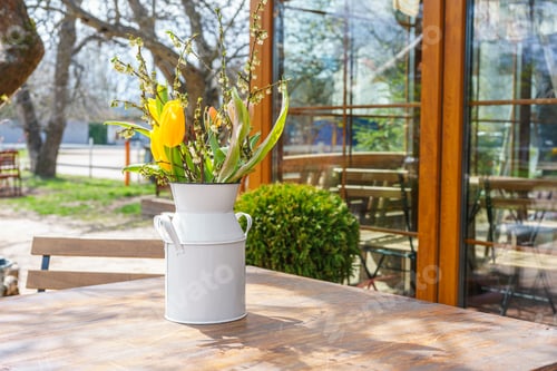Preview: Spring Bouquet Of Yellow Tulips And White Flowers In Rustic Metal Vase On Wooden Table Outdoors