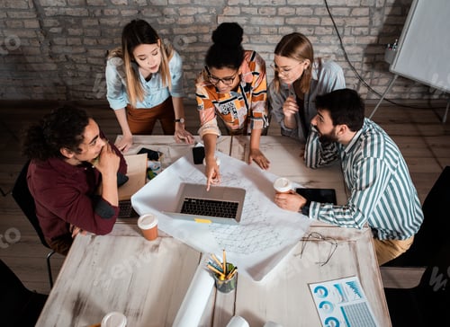 Preview: Group of modern business people in casual wear discussing architectural designs.