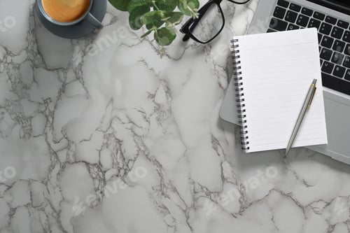 Preview: Blank notepad, laptop, eyeglasses and cup of coffee on marble table