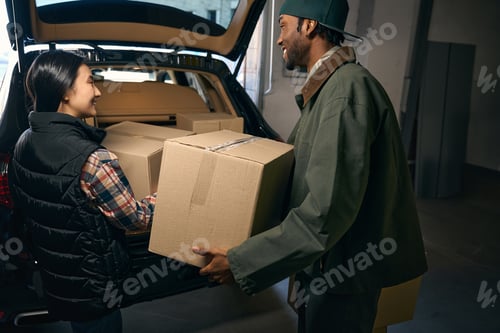 Preview: Happy smiling pair takes things out of a car in a storage service
