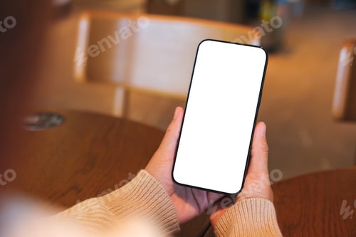 Preview: Mockup image of a woman holding and using mobile phone with blank desktop screen in cafe