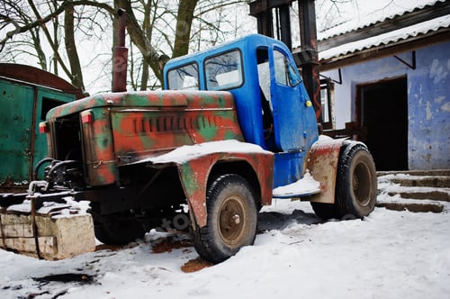Preview: Rusty old soviet tractor covered by snow.