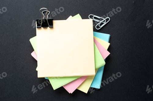 Preview: Close up view of stacked sticky note cubes paper clips on isolated black background with free space