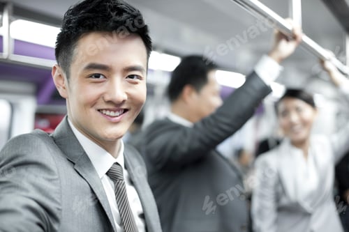 Preview: Cheerful businessman with partners in subway train