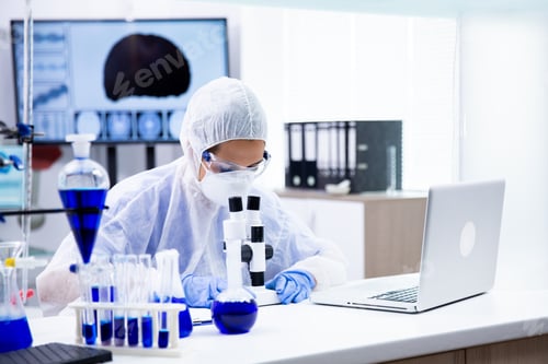Preview: Caucasian chemist who looks under the microscope and is surrounded by many tubes